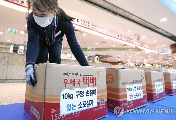 23일 서울중앙우체국에서 집배원이 구멍 손잡이가 있는 택배 상자를 옮겨 보고 있다.구멍 손잡이는 운반 편의를 위해 만들었다. (연합뉴스)
