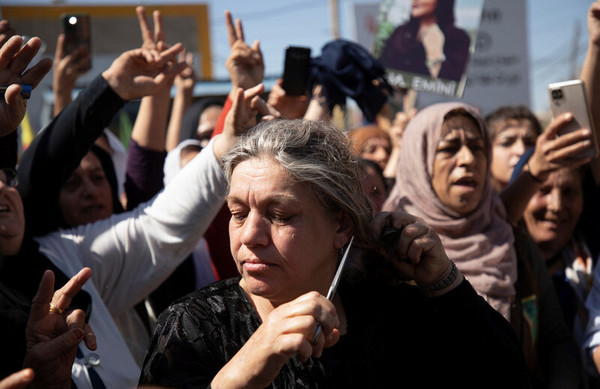 26일 시리아의 쿠르드족 밀집지역 콰미실에서 열린 히잡 반대 시위에서 한 여성이 자신의 머리카락을 자르고 있다. (로이터/연합뉴스)