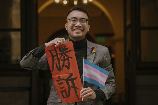 홍콩의 트랜스젠더 활동가 헨리 에드워드 쯔가 6일  종심법원 앞에서 트랜스젠더를 상징하는 깃발과 '승소'라고 적힌 종이를 들고 웃고 있다. (AP/연합뉴스]