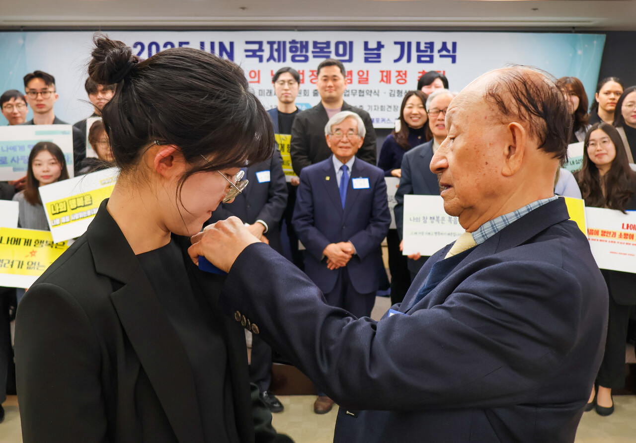 이은방 서울대 명예교수가 20일 박채은 이화여대 석박사 과정 학생에게 참행복나눔운동 배지를 달아주고 있다. (사진=참행복나눔운동)