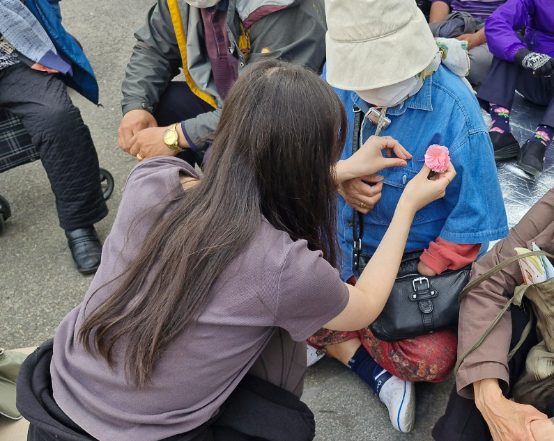 한 학생이 8일 서울역광장에서 할머니에게 카네이션을 달아주고 있다.(사진=참행복나눔운동)